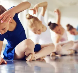 Girls sitting on floor in ballet pose in ballet outfits