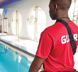 Male lifeguard watching over indoor pool