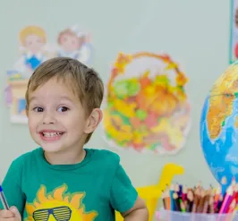 Smiling young boy sitting at table with art supplies and globe