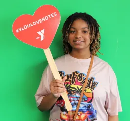 Youth in Love Notes program standing in front of green screen holding a #YLoveNotes sign