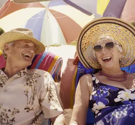 Two adults on a beach wearing hats and sunglasses