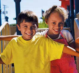 Two kids smiling at a playground