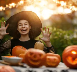 Teenage girl sitting at a table with jack-o-lanterns